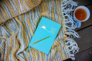 TAP IN journal on a blanket with tea gives tips on how to create a wellness retreat at home.